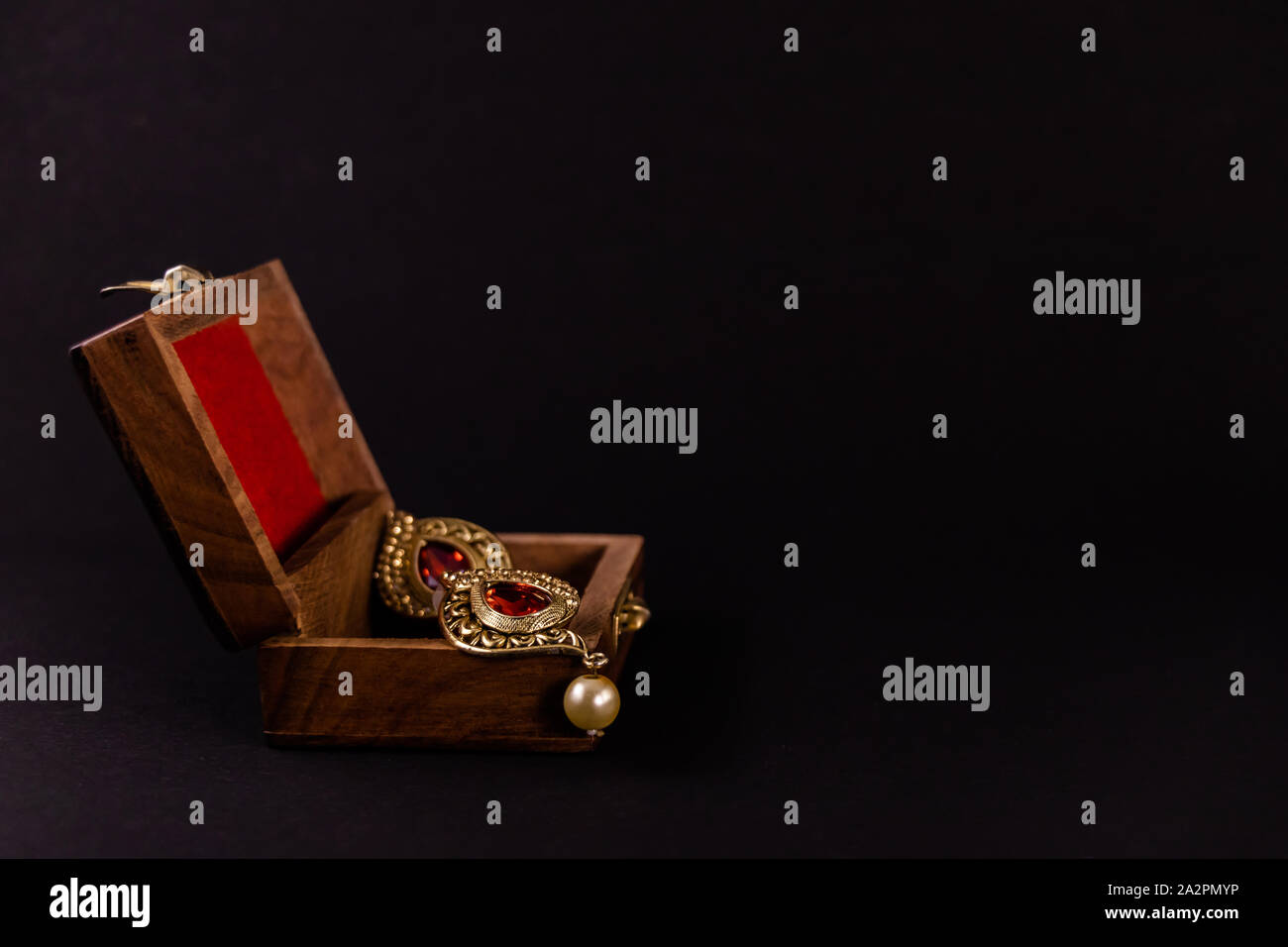 Paar Golden Earing in Holz- Geschenkbox auf schwarzem Hintergrund. Traditionelle Earing Geschenk Konzept Stockfoto