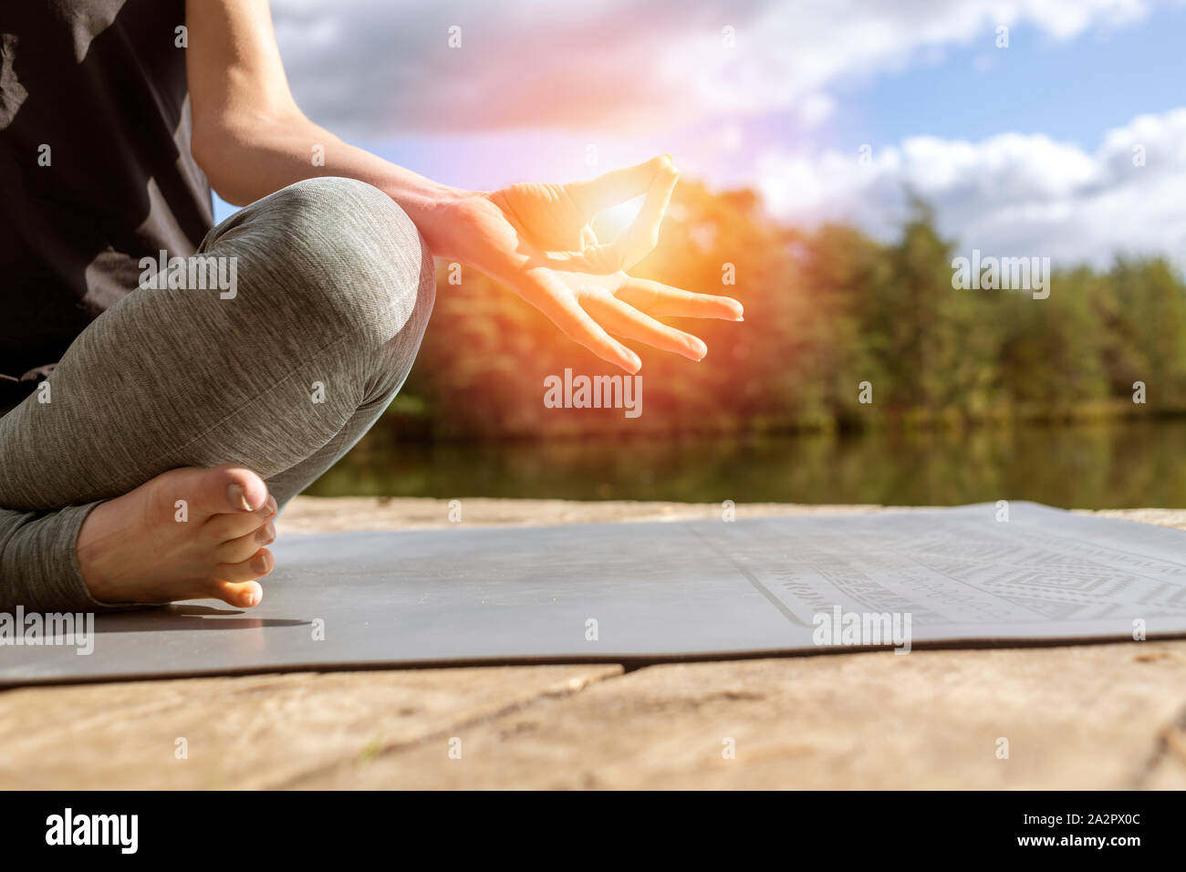 Frau sitzt an einem See Yoga in der Sonne Stockfoto