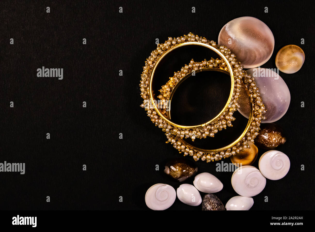 Traditionelle schmuck Konzept. Schöne vergoldete Pearl Armreifen mit Muscheln auf schwarzem Hintergrund Stockfoto
