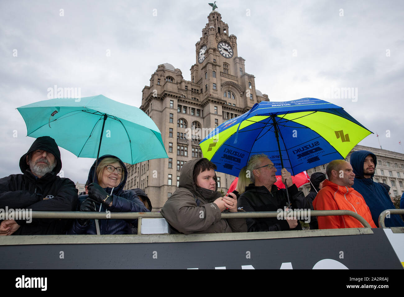 Liverpool, Großbritannien. 3. Okt, 2019. (L), Fans Unterschlupf vor dem Regen unter Sonnenschirmen am Pier Head, vor dem Beginn des Wales Rally GB, Kredit: Jason Richardson/Alamy leben Nachrichten Stockfoto