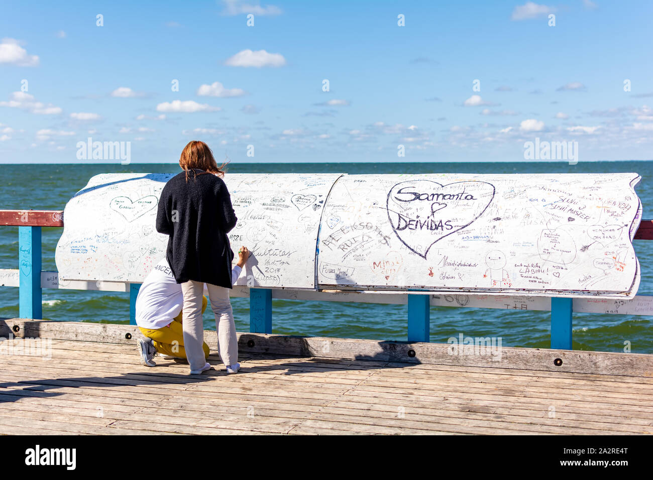 Zwei nicht identifizierte Mädchen verlassen ihre Inschriften auf spezielle Board bei berühmten Pier im beliebten Badeort Palanga, Litauen. Stockfoto