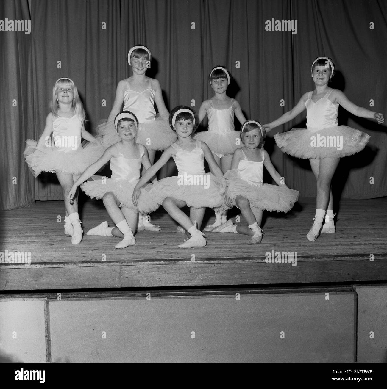 1960er Jahre, historisches Schulballett, auf einer Holzbühne posiert eine Gruppe junger Mädchen in ihren Ballettkostümen - ein Kleid, das als Tutu bekannt ist - anmutig für ein Foto, England, Großbritannien. Das Wort Ballett bedeutet "kleiner Tanz". Stockfoto