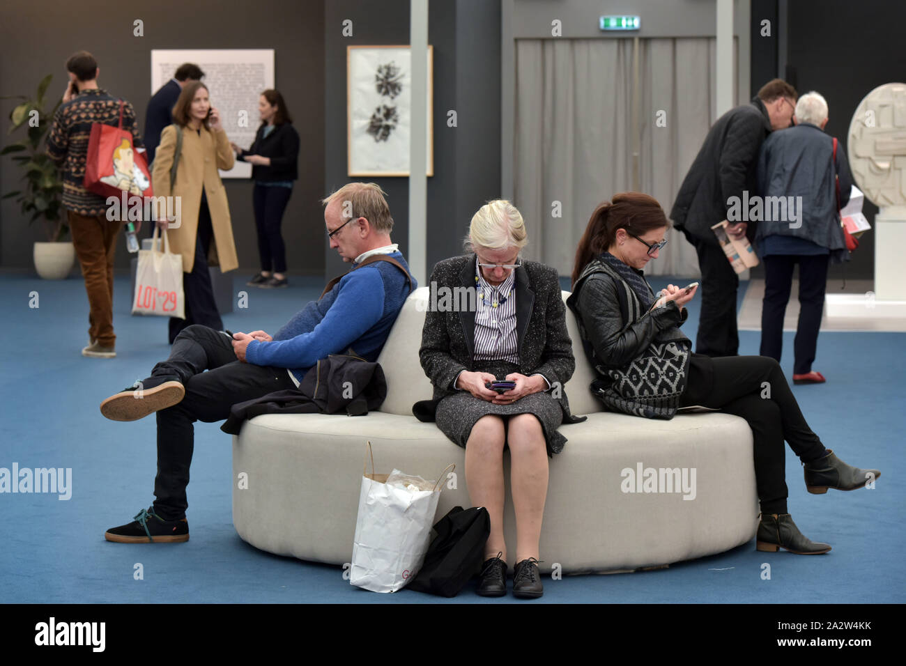 Mitglieder der Öffentlichkeit, Kunstliebhaber und Sammler sprechen auf ihren Mobiltelefonen und Ihre Nachrichten zu überprüfen, da sie die öffnung Tag der Kunstmesse F teilnehmen Stockfoto