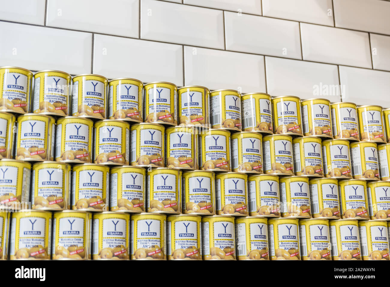 Stapel der Oliven Dosen gegen einen weiß gefliesten Wand Stockfoto