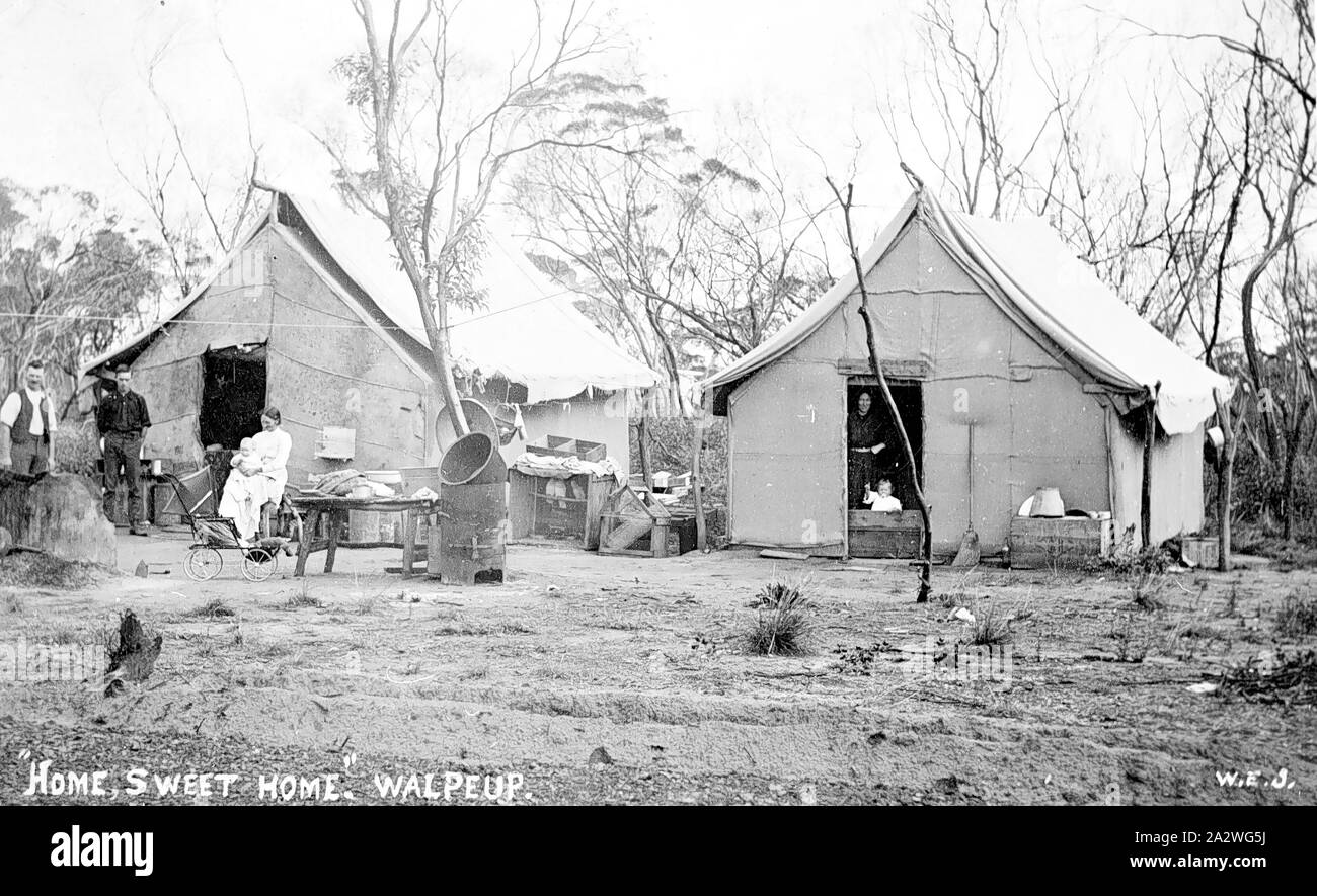 Negative - Walpeup, Victoria 1911, der Simpson Familie vor ihrem Haus bei Walpeup. Ihre Häuser sind Zelte aus hessischen Taschen konstruiert zusammen genäht und über einen Holzrahmen befestigt. Verschiedene Möbel und Utensilien auf Tischen im Freien. Ein kleines Kind schaut aus dem Inneren eines der Zelte Stockfoto