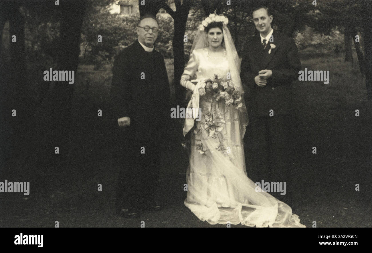 Fotografie - James & Eileen Blutegel mit Pastor, Manchester, England, 1949, schwarz-weiß Foto von James und Eileen Blutegel mit der Kirche Minister bei ihrer Hochzeit stehen. Es ist eines von sechs schwarz-weiß Fotografien in einer Hochzeit Album von James und Eileen Leech Trauung in Manchester, England, 1. August 1949 enthalten. Das Album wurde unter Besitz mit sich gebracht, als sie nach Australien ausgewandert 1953 und auch unter denen brachten sie zurück zu Stockfoto