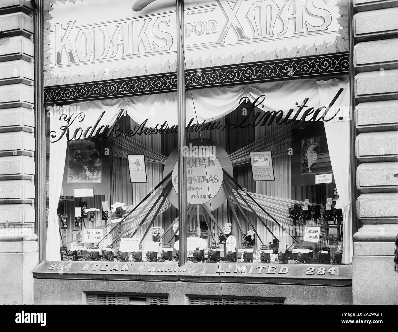 Glas Negative - Kodak Australasia Ltd, Weihnachten Shopfront angezeigt, Block Arcade, 284 Collins Street, Melbourne, 1911-1920, Schwarz und Weiß, Glasplatte negativ der Kodak Australasien begrenzt Retail shopfront im Block Arcade, 284 Collins Street Melbourne, ca. 1911 bis 1920. Die Anzeige verfügt über mehrere Kameras, markiert als "präsentiert" und eine dekorative Sunburst von Material mit einer kreisförmigen Zeichen in der Mitte sagen: "Eine Kodak an Weihnachten ist immer willkommen Stockfoto