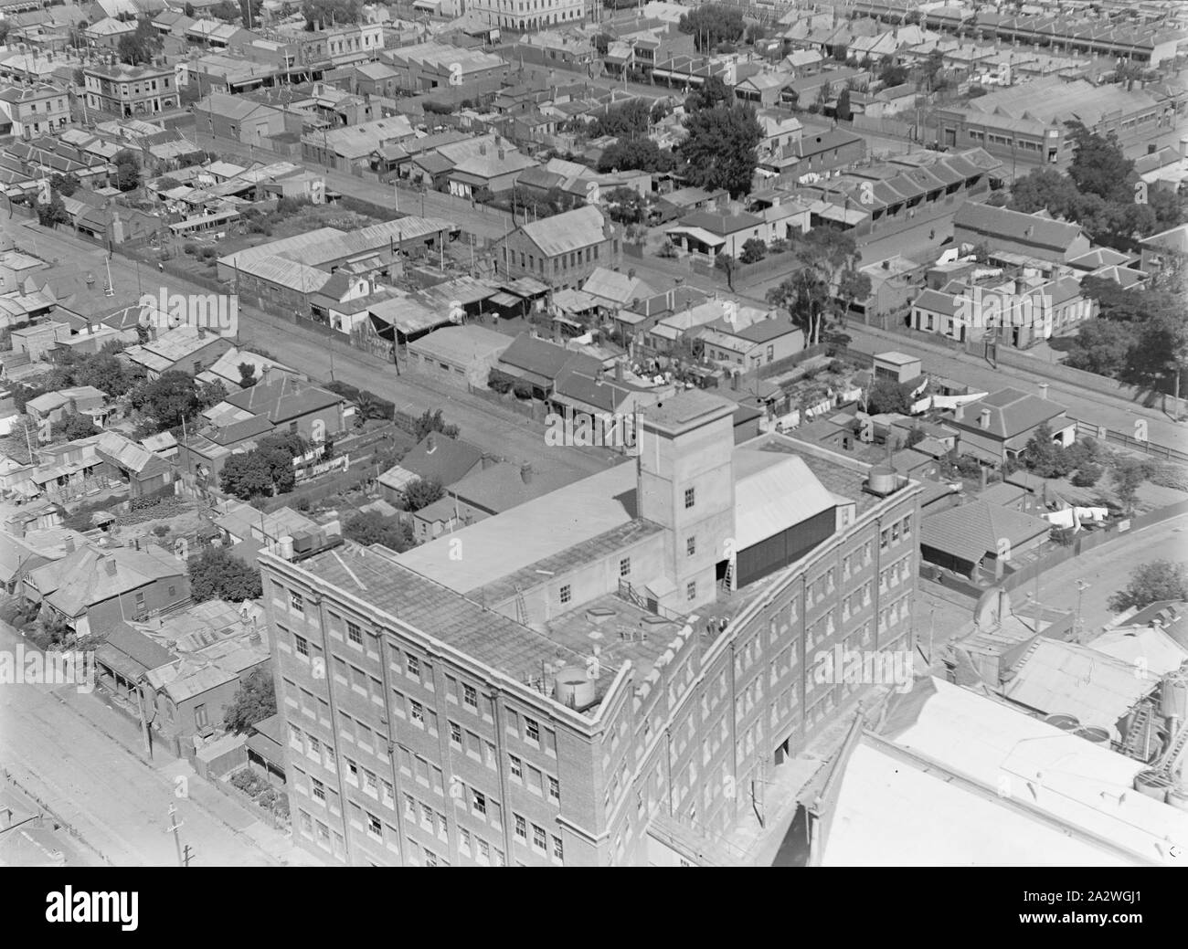 Glas Negative, Fabrik Luftbild 6, Abbotsford, Victoria, circa 1930s, Schwarz und Weiß, die Hälfte Platte Glas negative mit einem Luftbild des Kodak Australasia Pty Ltd Fabrik in Abbotsford, ca. 1930er-Jahre. Diese schrägen Blick auf die geschwungene, mehrstöckiges Ziegelgebäude an Southampton Crescent, Wassertank, Treppen und Lüftungsschlitze deutlich sichtbar. Suburban Straßen und Häuser umgeben es. Dies ist einer von neun schwarze und weiße Hälfte platte Glasnegative in Einem Stockfoto