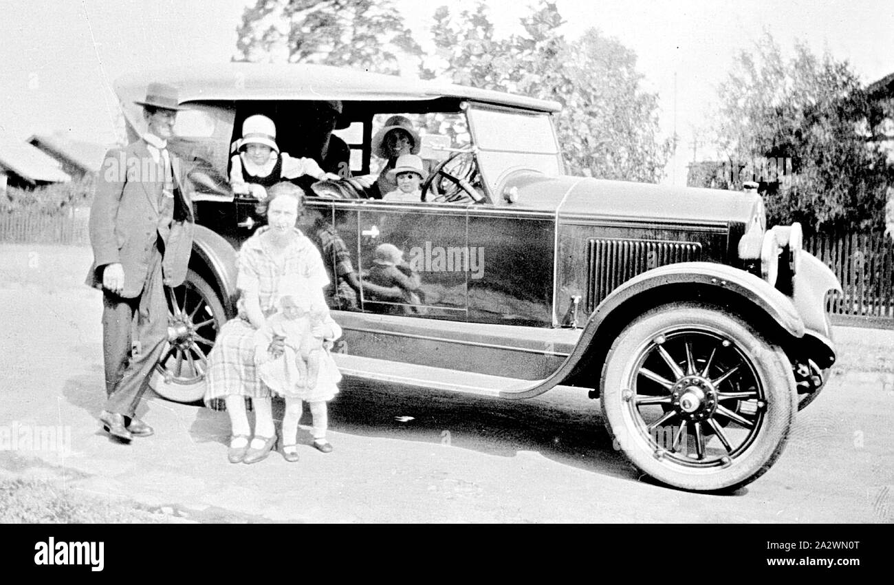 Negative - Familienausflug in einem Armstrong Siddeley Motor Car, Malvern East, Victoria, 1926, ein Familienausflug in einem Armstrong Siddeley Motor Car. Eine Frau sitzt auf dem Trittbrett mit einem kleinen Kind. Vier andere Blick von innen im Auto Stockfoto