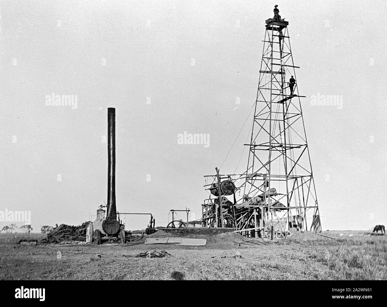 Negative - Männer auf einen artesischen Bohrung Turm auf 'Portland Downs' Bahnhof, Isisford Bezirk, Queensland, ca. 1915, Männer auf einen artesischen Bohrung Turm auf 'Portland Downs" Station. Die Dampfmaschine auf der linken Seite verfügt über eine extrem hohe Trichter Stockfoto