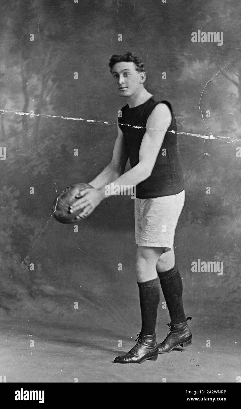 Negative - Collingwood, Victoria, 1916, Harold Walker, der war ein bekannter Läufer und Fußballspieler, posiert mit einem Fußball Stockfoto