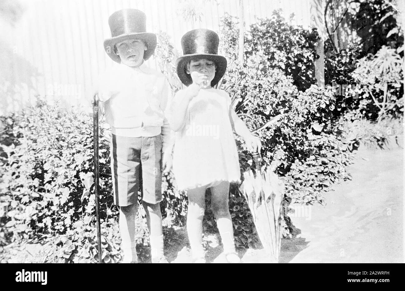 Negative - Euston District, New South Wales, ca. 1925, ein kleines Mädchen und junge, beide trugen große top Hüte. Das Mädchen hält einen Sonnenschirm und der Junge einen Stock Stockfoto