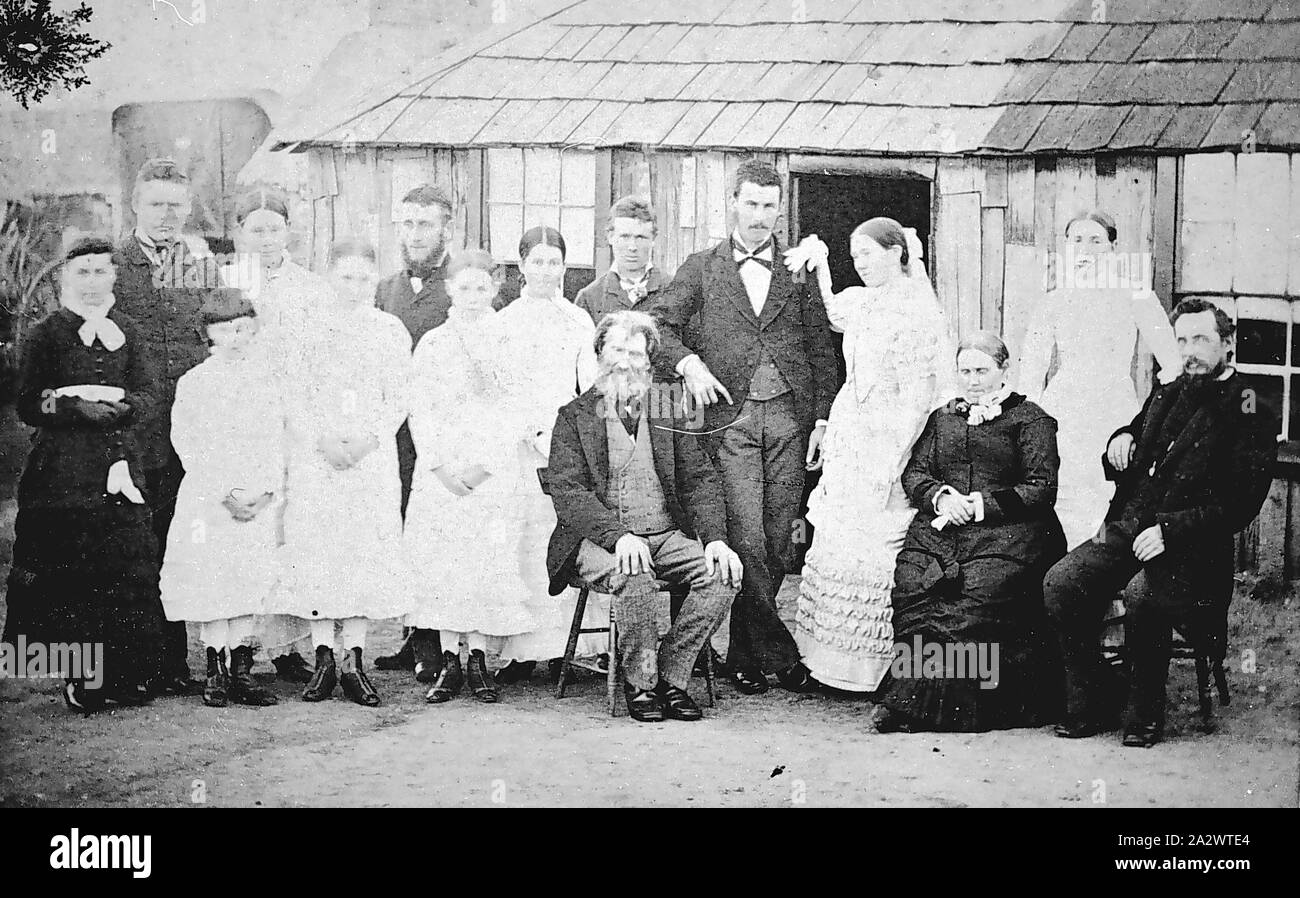 Negative - Victoria, ca. 1875, eine Hochzeit Gruppe außerhalb einer Platte Hütte versammelt. Ein älterer Mann und Frau sind in der Front und die Braut und der Bräutigam stand hinter ihnen sitzt Stockfoto