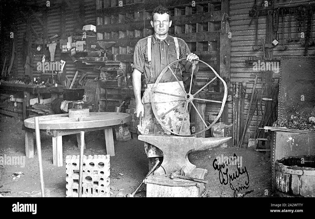 Negative - penong District, South Australia, circa 1915, ein Mann, der die Reparatur eines Rades in einer Schmiede." Mit freundlichen Grüßen, Jim" hat auf dem Foto geschrieben worden Stockfoto