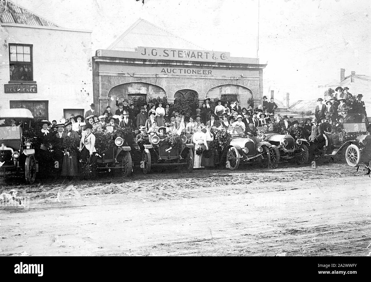 Negative - Portland, Victoria, 1915, eine Masse von Menschen mit einer Linie der Autos (von denen einige mit Flechtwerk Zweige eingerichtet) vor J. G. Stewart & Company, Auktionator Stockfoto