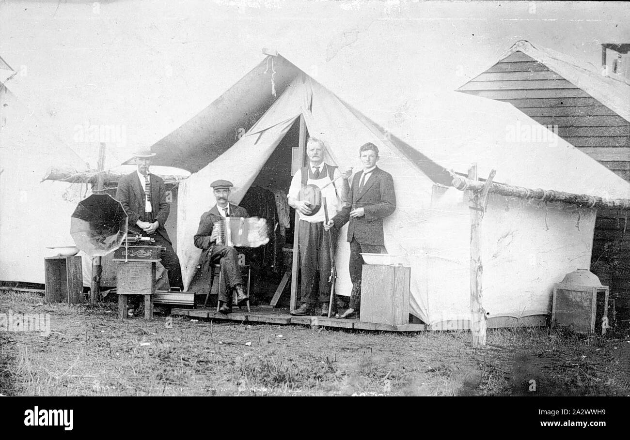 Negative - Waddamana (?), Tasmanien, ca. 1925, vier Männer vor einem Zelt. Man sitzt mit einem grammophon, hat man ein Akkordeon, ein Banjo, während der vierte Mann hält eine Pistole. Es ist ein Gebäude aus Holz hinter dem Zelt Stockfoto