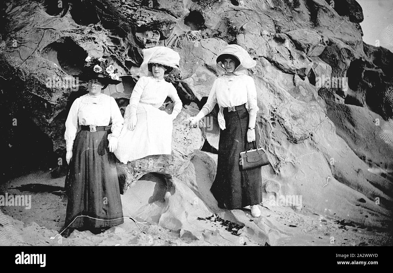 Negative - Easton Familie auf einem Felsvorsprung am Strand, Kilcunda, Victoria, 1912, schwarz-weiß Foto von Charlotte Easton [links] und zwei ihrer Töchter, Laura Mai und Florenz Maria, an der Basis von einem Felsvorsprung am Strand von Kilcunda, Victoria im Jahr 1912. Charlotte (geborene Philbrick) Easton's Ehemann war William Challis Easton, eine Bäckerei und Teestuben in Wonthaggi ran und wurde später der Bürgermeister von wonthaggi. Er starb im Jahre 1945. William und seinem älteren Bruder Challis Stockfoto