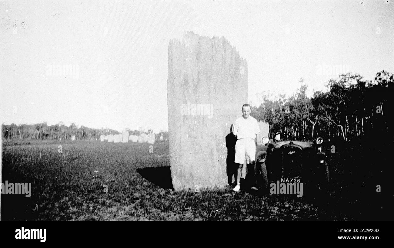 Negative - Mann steht zwischen einem Austin Seven Auto & Ant Hill, Northern Territory, circa 1930, ein Mann steht zwischen einem Austin Auto und ein Ameisenhaufen Stockfoto