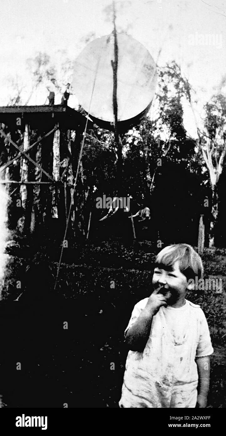Negative - Barooga District, New South Wales, ca. 1930, im Hintergrund ein Wassertank auf einem hohen Plattform auf 'Murray Park" Station installiert wird. Ein kleines Kind steht im Vordergrund Stockfoto