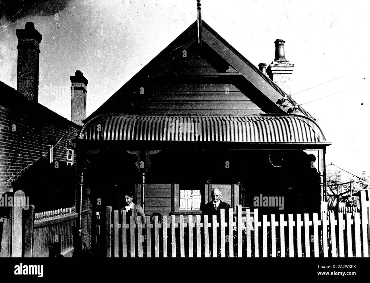 Negative - Sydney, New South Wales, ca. 1930, ein Mann und eine Frau vor einem kleinen Holzhaus. Die Veranda ist mit einem Wellblechdach Stockfoto