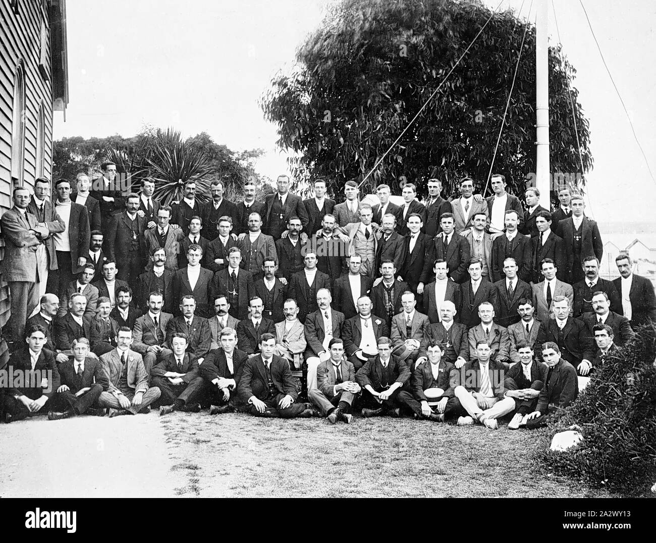 Negative - Barwon Heads, Victoria, 1914, Hawkes Brüder Diamond Jubilee Picknick. Die all-männliche Gruppe ist hinter einem Gebäude, die von den Fenstern, eine Kirche werden gesammelt Stockfoto