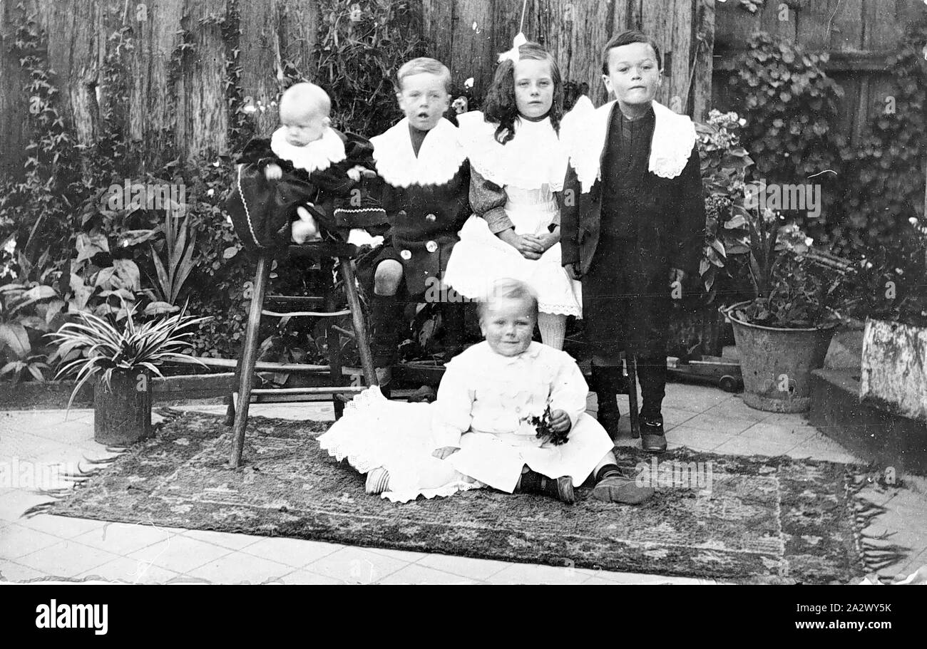 Negative - Victoria, ca. 1905, fünf sehr gut gekleidet Kinder in einem Hinterhof. Das Baby sitzt auf einem Stuhl und einem Kleinkind sitzt auf einem Teppich vor der Gruppe Stockfoto