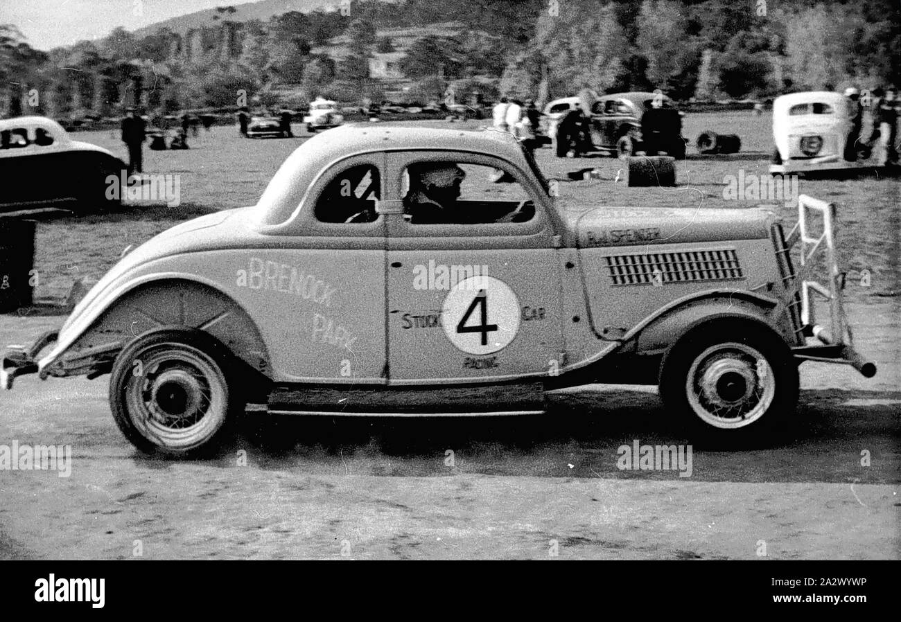 Negative - Victoria, ca. 1955, ein Auto in Brenoch Park. Es gibt eine große Anzahl vier an der Tür des Autos. Es gibt einen Mann, der im Auto sitzen, und andere Männer und Autos können im Hintergrund gesehen werden. Stockfoto