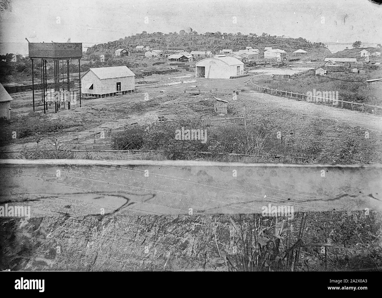 Negative-Port Darwin, Northern Territory, circa 1880, Gebäude in Port Darwin. Es gibt einen Wassertank auf der linken und der Eisenbahnstrecken im Hintergrund. Es gibt einen Zaun Schiene an der Vorderseite der Foto Stockfoto