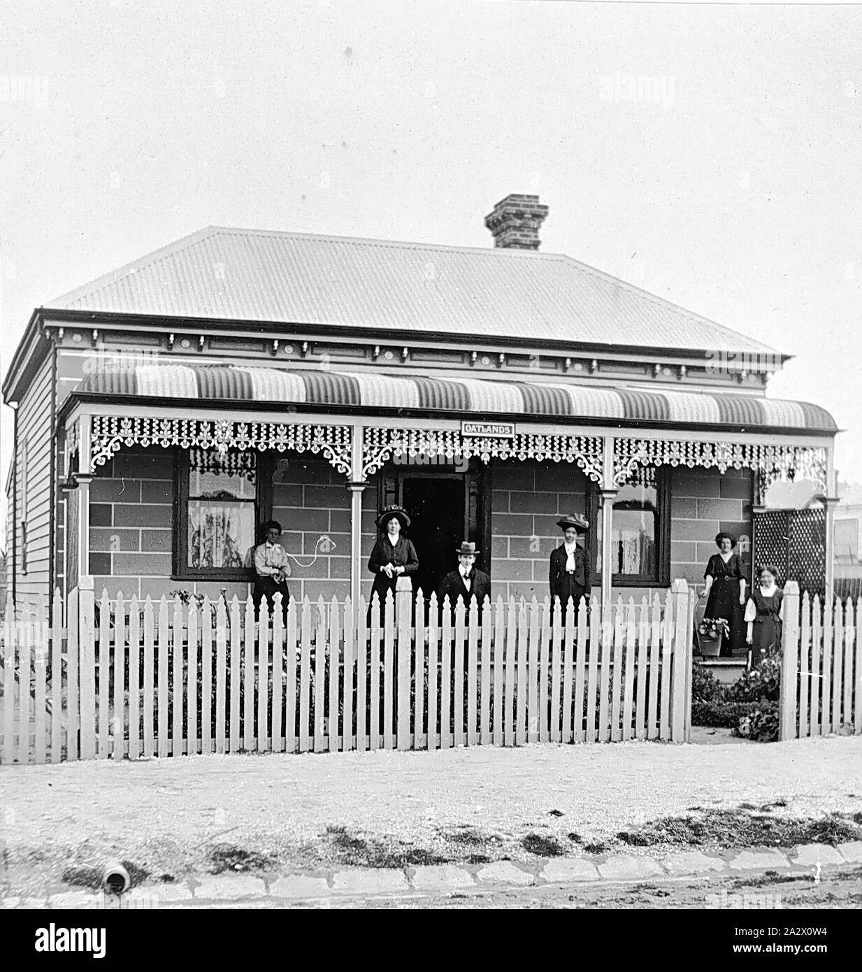 Negative - Bendigo, Victoria, um 1910, eine Familie, die auf der Veranda ihres Hauses gesammelt. Sie sind in ihren besten Kleidern. Es ist eine falsche Backsteinfassade des weatherboard Haus Stockfoto