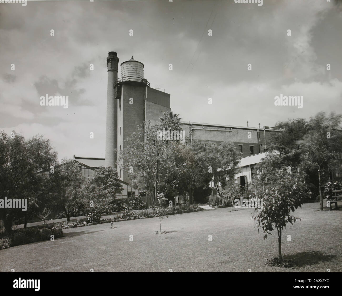 Fotografie, Kodak Factory & Gärten, Abbotsford, Victoria, circa 1930s, Schwarz und Weiß Silber Gelatine Foto von der Außenseite des Kodak Fabrik in Abbotsford, Victoria, ca. 1930er Jahre (vor 1948). Im Vordergrund dieses Foto zeigt das Personal Gärten, Beete, Bäume, Rasen und Garten sitze. Dieser Bereich wurde in der Nähe der Kantine, die niedrige Fibro und Gebäude auf der rechten Seite, wo die Mitarbeiter ihre Pausen. Auf der linken Seite der Fotografie, Teil Stockfoto