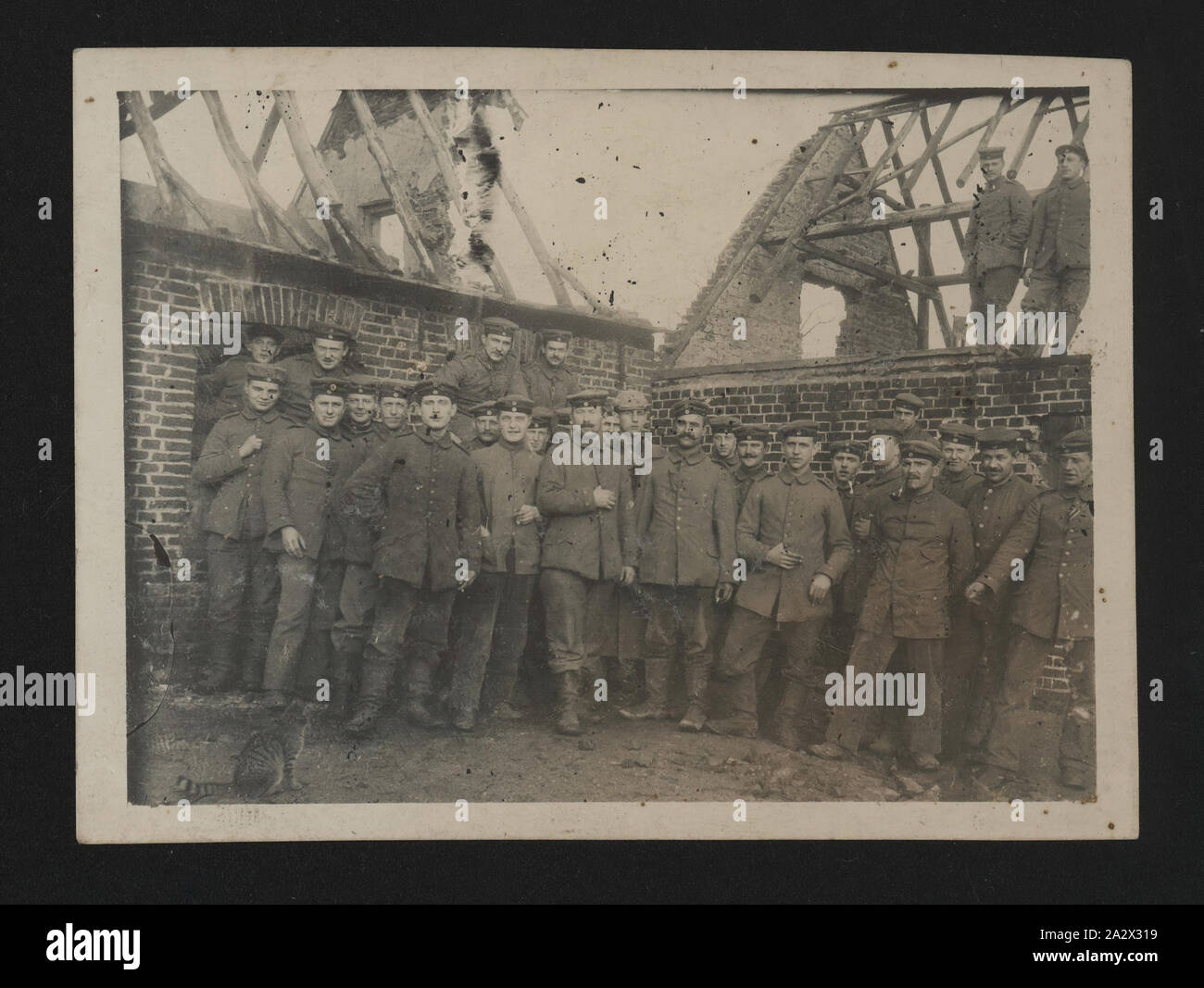 Fotografie - deutsche Soldaten in Ruinen, 1914-1918, Foto, 29 deutsche Soldaten vor der Reste von zwei beschädigte Backsteinbauten. Sie können in einem Bauernhof. Sie schauen entspannt; man ist das Rauchen. Die Herkunft des Fotos ist unbekannt, obwohl es bis zum Ersten Weltkrieg vom Ich ist Stockfoto
