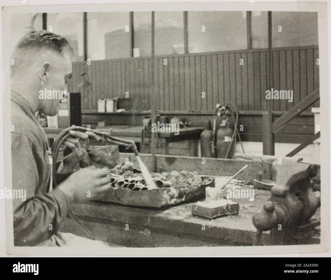 Fotografie - Hecla Elektrik Pty Ltd., ein Arbeiter, Schweißen, ca. 1920, schwarz-weiß Foto eines Hecla Factory Mitarbeiter an Werkbank Schweißen dünne Metallrohre sitzt, ca. 1920. Dieses Foto ist von einem Album mit 255 schwarz-weiß Fotos, Elektrogeräte, Showroom zeigt, Fabrik Interieur- und Werbematerial im Zusammenhang mit Hecla Elektrik Pty Ltd. ist Teil der Hecla Sammlung von Fotografien, Dokumente, Produkte Stockfoto