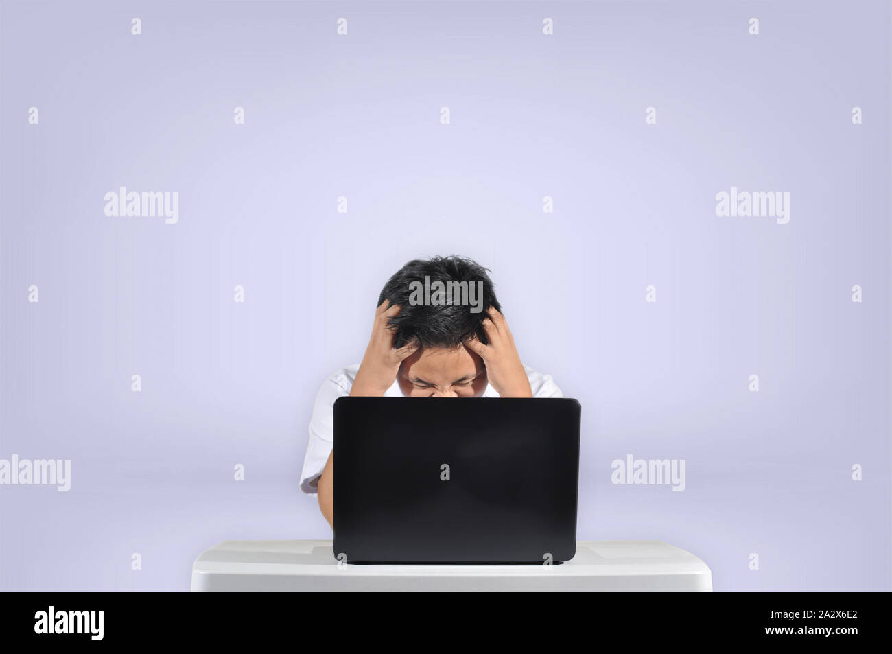 Junge männliche Kursteilnehmer wütend vor seinem Laptop dabei sein Projekt oder einer Aufgabe Konzept in einem weißen Hintergrund isoliert frustriert. Stockfoto