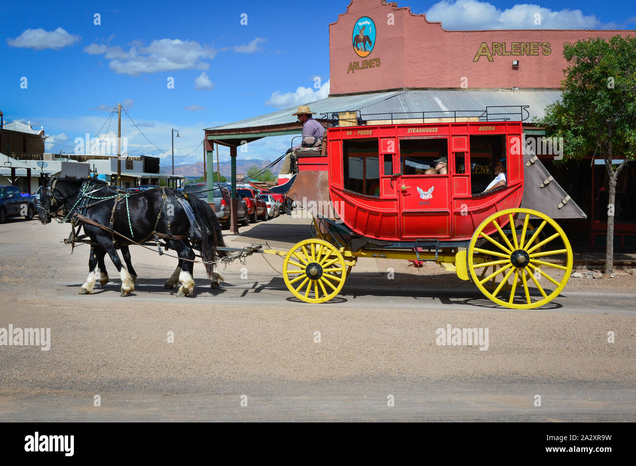 Eine rote und gelbe antiken Stagecoach von zwei Pferden geführt von Cowboy Treiber mit Touristen in Tombstone, AZ, USA an Bord gezogen Stockfoto