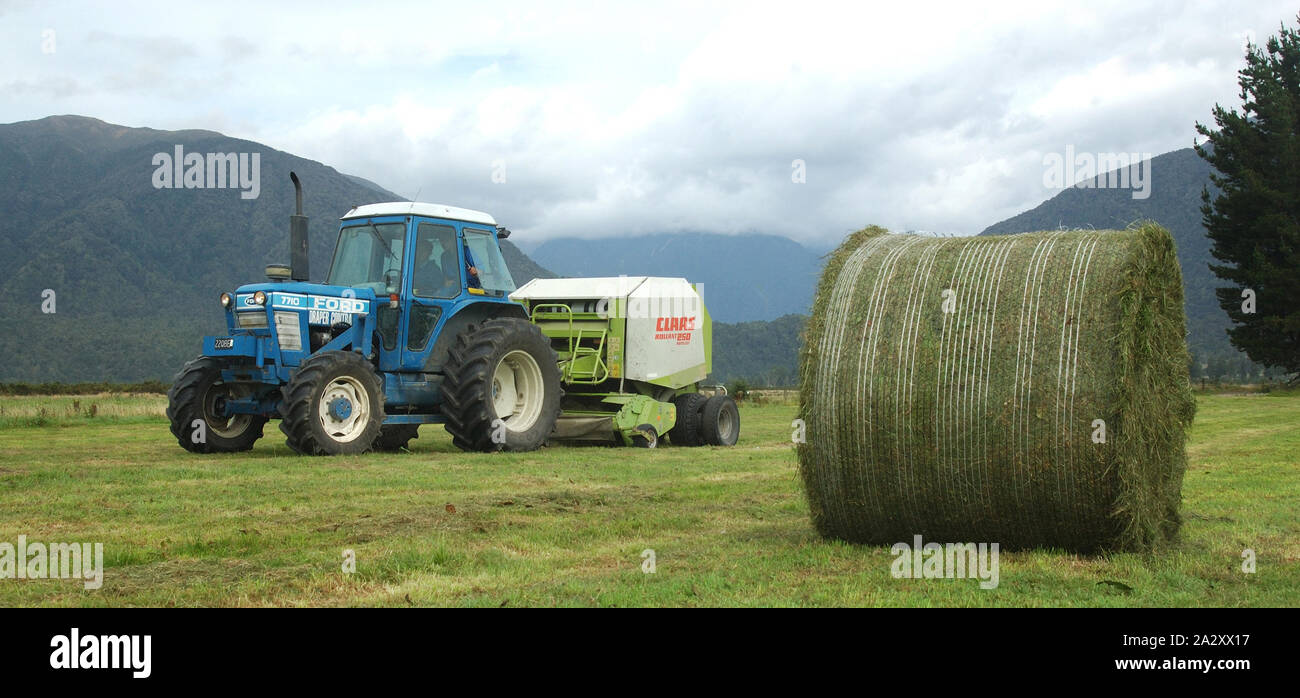 Greymouth, Neuseeland, 22. Februar 2008: Schlepper Pressen bis großen Rundballen des Grases für Silage, West Coast, South Island, Neuseeland Stockfoto