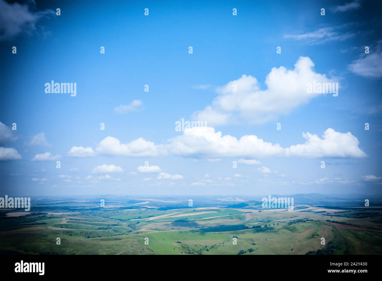 Schönen landschaftlichen Hintergrund mit Vignette, blauer Himmel mit Wolken, Landschaft und Wiesen in einer hügeligen Gegend. Grußkarte oder Rahmen für Text mit der Stockfoto