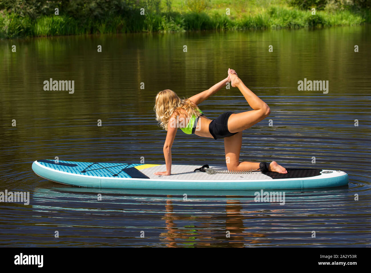 Junge kaukasier Frau auf SUP in yoaga Pose auf dem Fluss Stockfoto