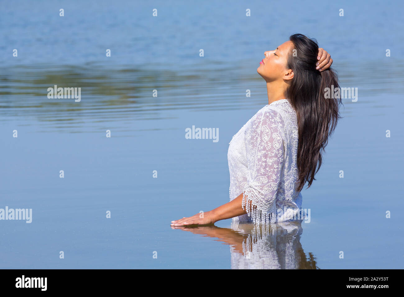 Kolumbianische Frau mit langen schwarzen Haaren und weiße Kleidung steht in natürlichen See Stockfoto