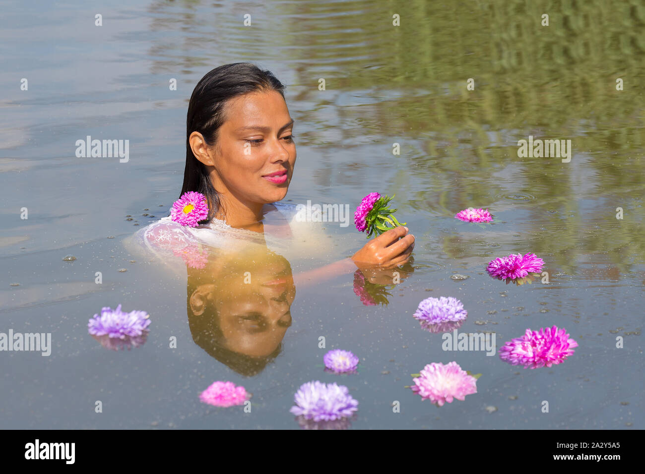 Portrait von kolumbianischen Frau in Wasser mit bunten Blumen Stockfoto