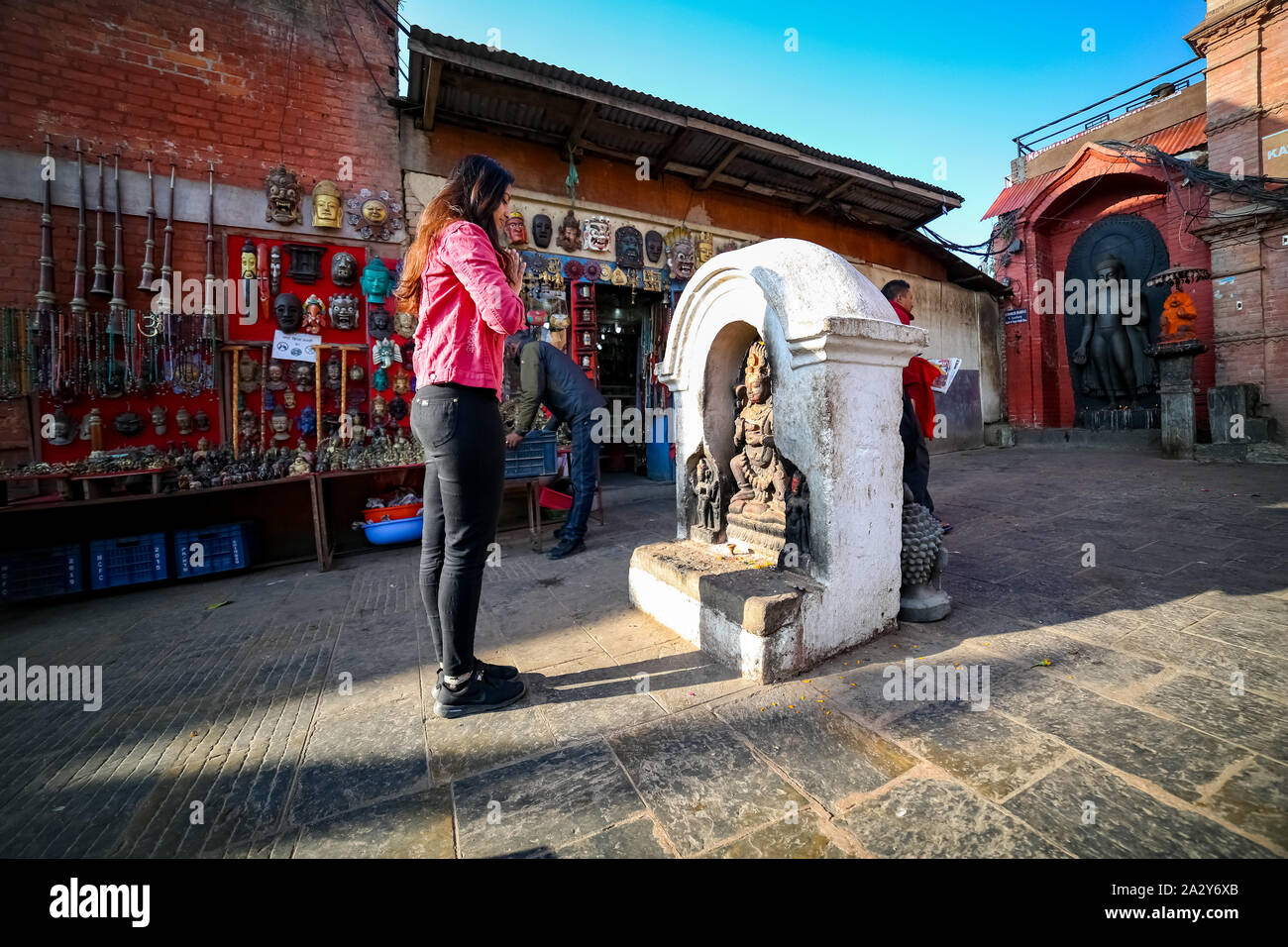 Junge Buddhistische Anhänger Mädchen beten vor einem Buddha Statue im Kloster in Nepal Swayambhunath Stockfoto