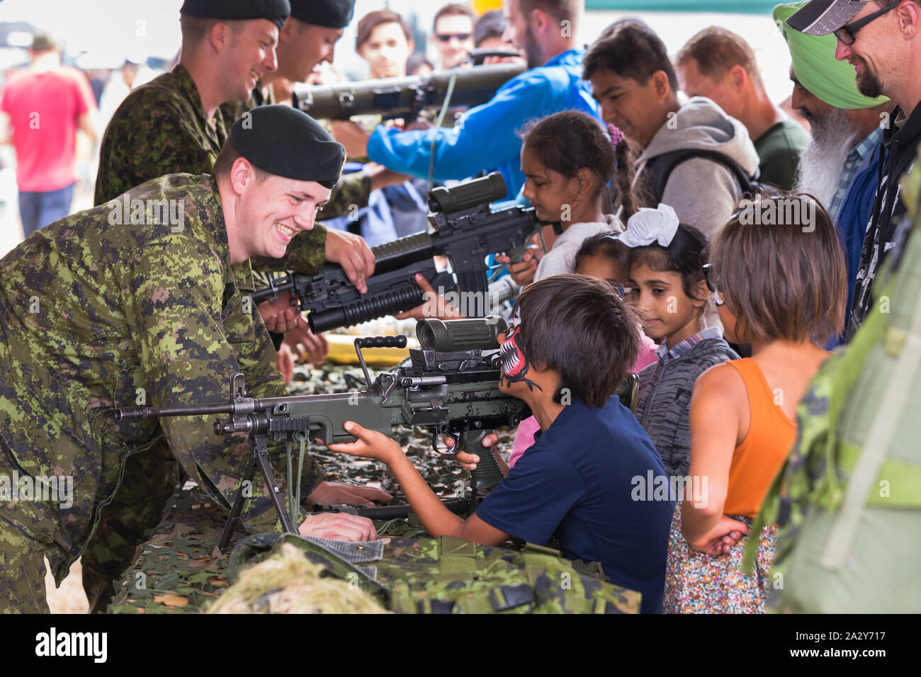 ABBOTSFORD, BC, KANADA - 11. AUG 2019: Ein Soldat der kanadischen Streitkräfte zeigt Kindern auf der Abbotsford International Airshow ein automatisches Gewehr. Stockfoto