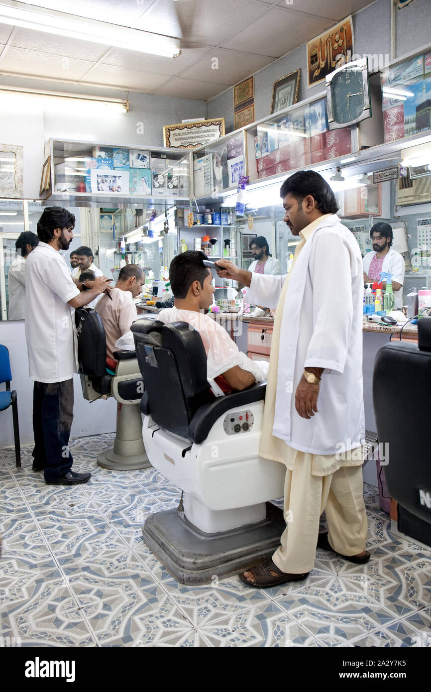 Arabisch Mann mit Bart bedeckt mit weißen Cape sitzt in Friseure Stuhl, Schönheit liefert Hintergrund. Mann mit Bart client der Hipster barbershop Stockfoto