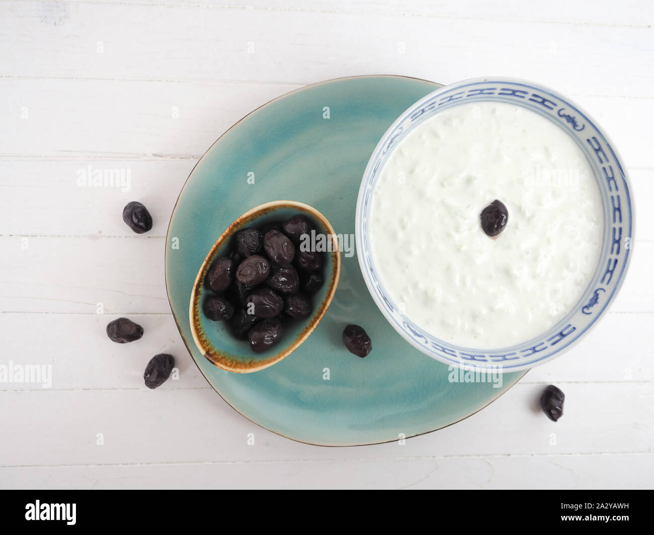 Traditionell griechischer Joghurt Gurken Knoblauch Appetizer namens Tzatziki auf retro Platten mit Oliven und weißen Holzmöbeln Platte Stockfoto