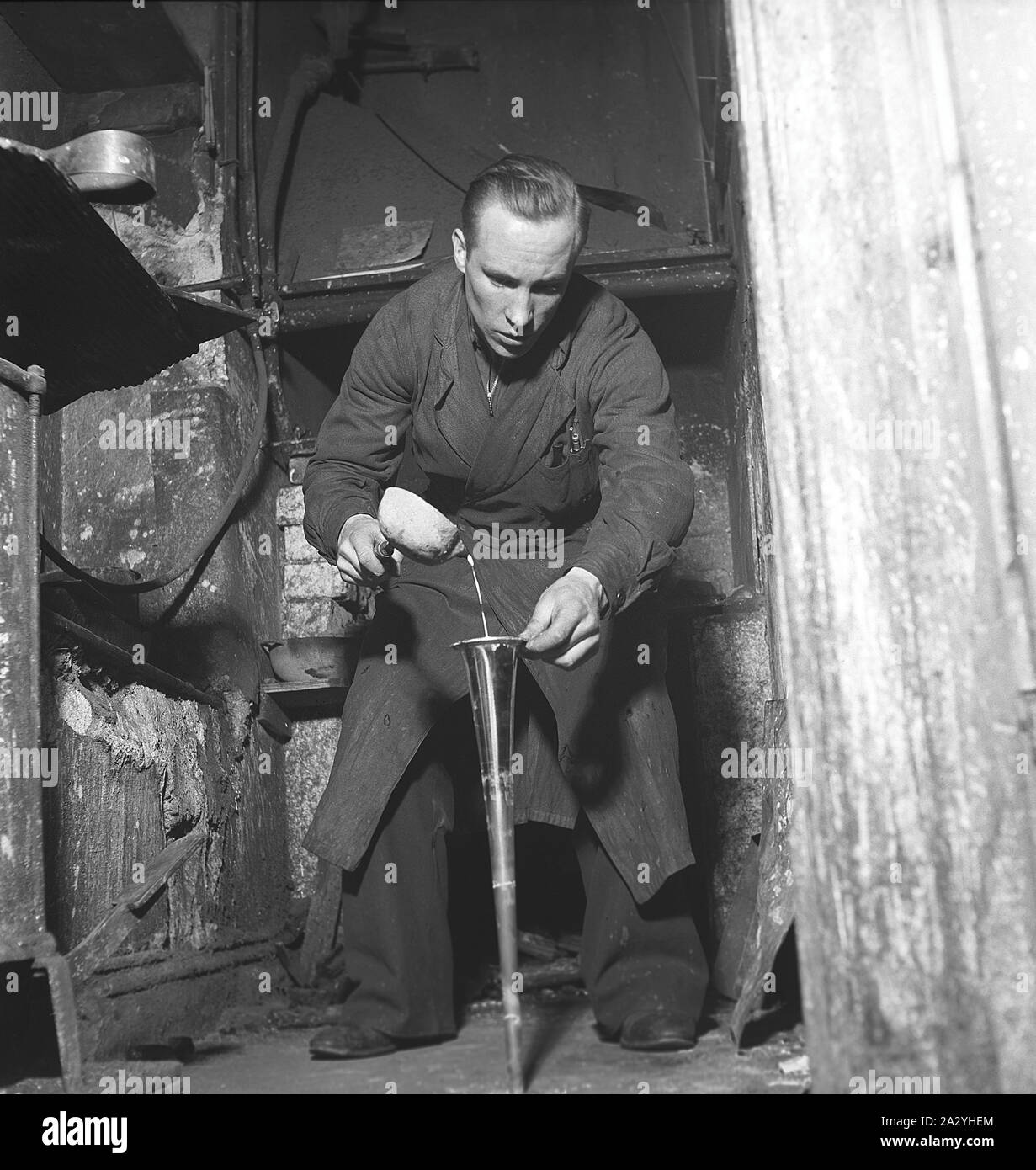 Die Arbeiter in den 1940er Jahren. Innenraum eines mechanischen Werkstatt für Musikinstrumente, wo ein Mann Zinn Gießen ist in eine Messing Horn. Schweden 1941 Kristoffersson Ref. 225-2 Stockfoto