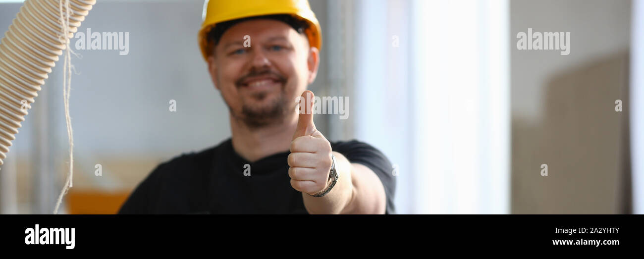 Lächelnd Arbeiter in gelben Helm zeigen Zeichen bestätigen Stockfoto