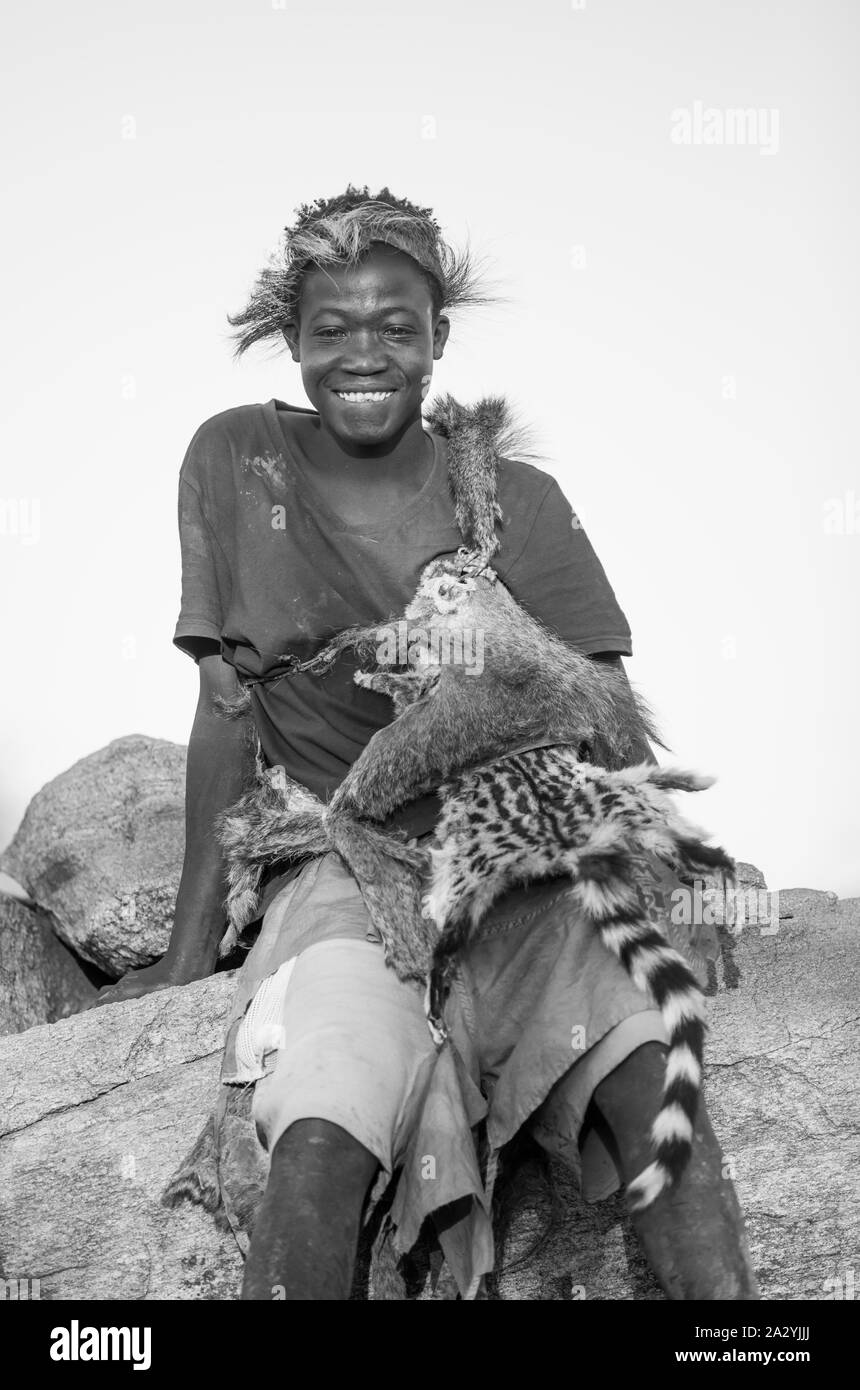 Lake Eyasi, Tansania, 11. September 2019: Hadzabe jungen Mann in der Tanne Kleidung, ruhenden Stockfoto