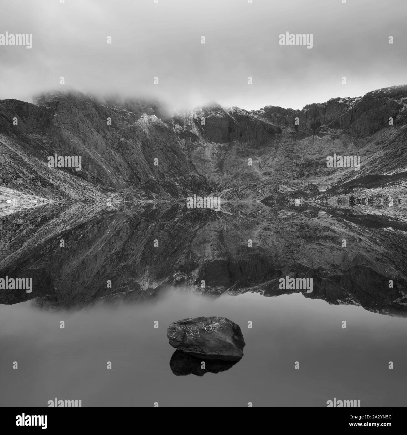 Atemberaubende dramatische Winterlandschaft Bild von Llyn Glyders Idwal und schneebedeckten Bergkette in Snowdonia in Schwarz und Weiß Stockfoto