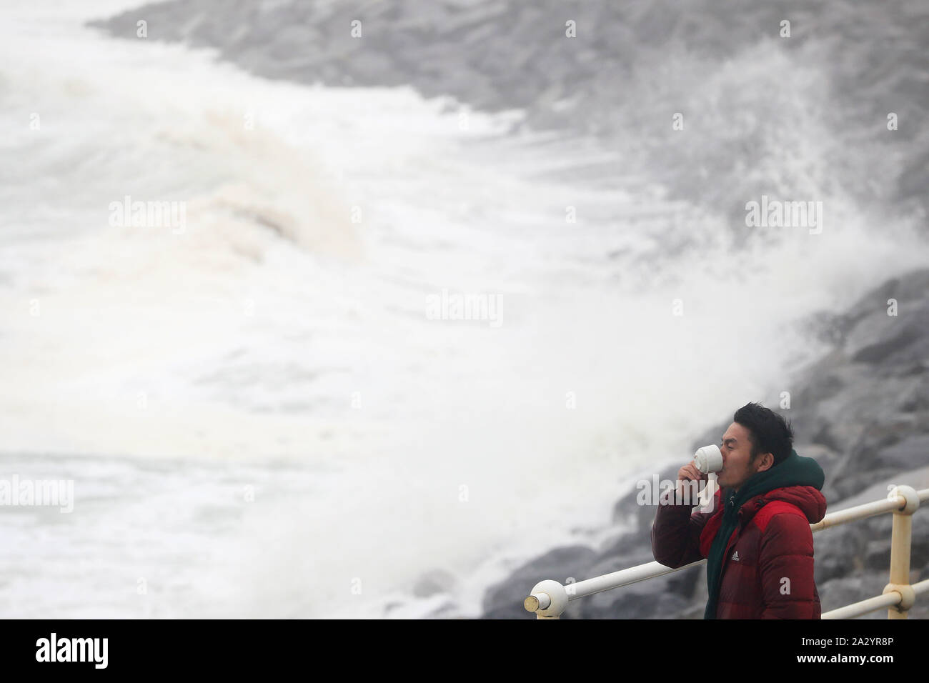 Ganaa Devee, ein Surfer aus der Mongolei, Uhren die Wellen am Meer entlang in Lahinch, County Clare, an der Westküste von Irland, in der sich Tausende von Haushalten und Unternehmen ohne Strom geblieben sind als Sturm Lorenzo in ganz Irland. Stockfoto