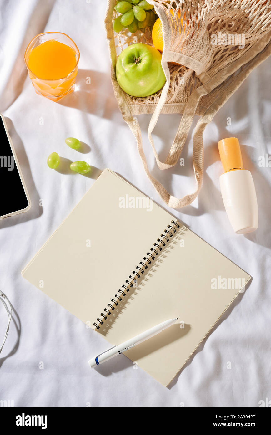 Sommer - Picknick Konzept. Notebook, Obst, Tasche, Stroh, Hut, Sonnencreme, Kamera und Sonnencreme auf weißem Hintergrund. Stockfoto