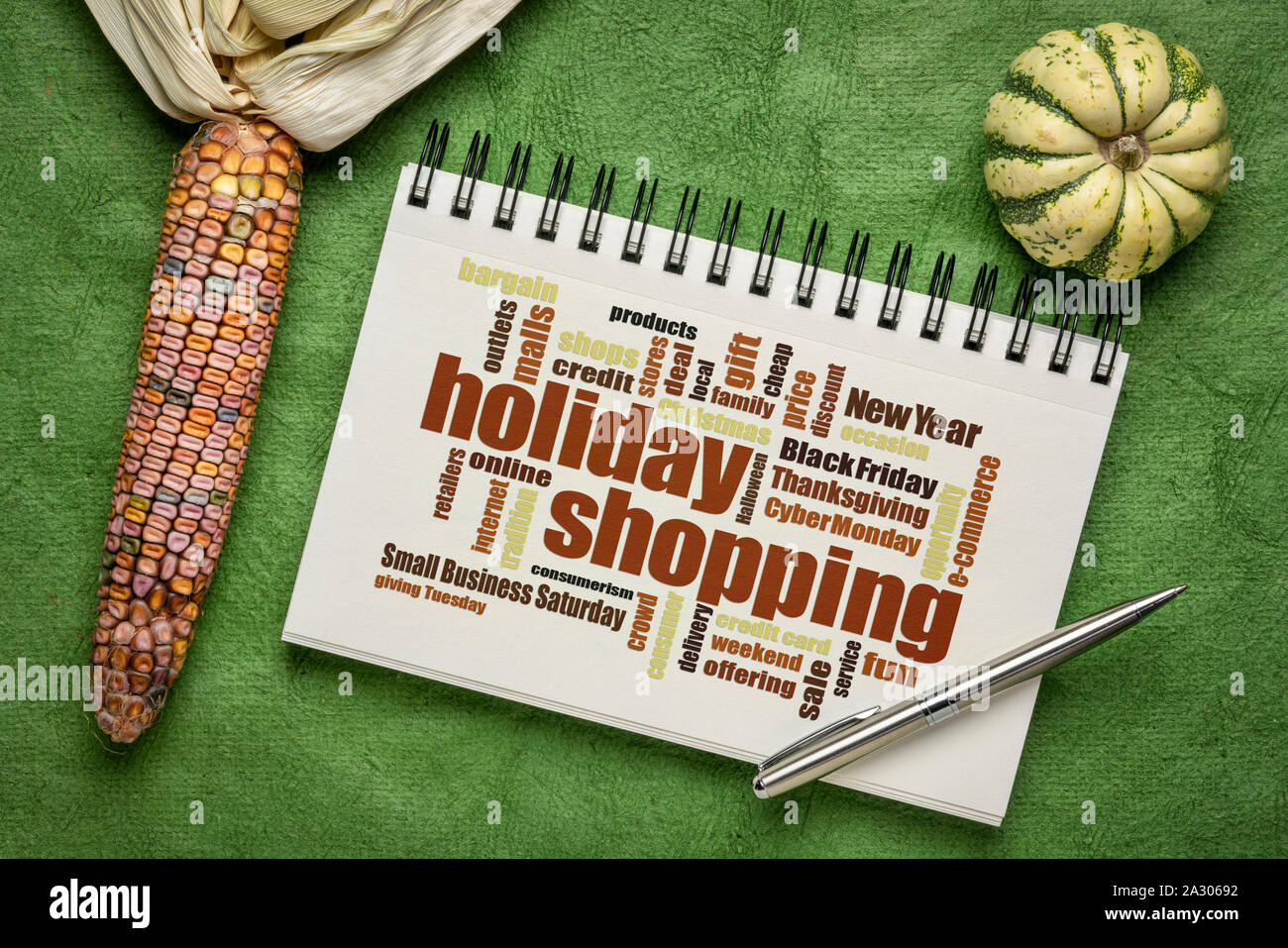 Holiday Shopping Wort Wolke in einem Skizzenbuch mit dekorativen Mais und Kürbis Stockfoto